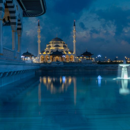 Gece aydınlatmasıyla havuza yansıyan modern bir cami